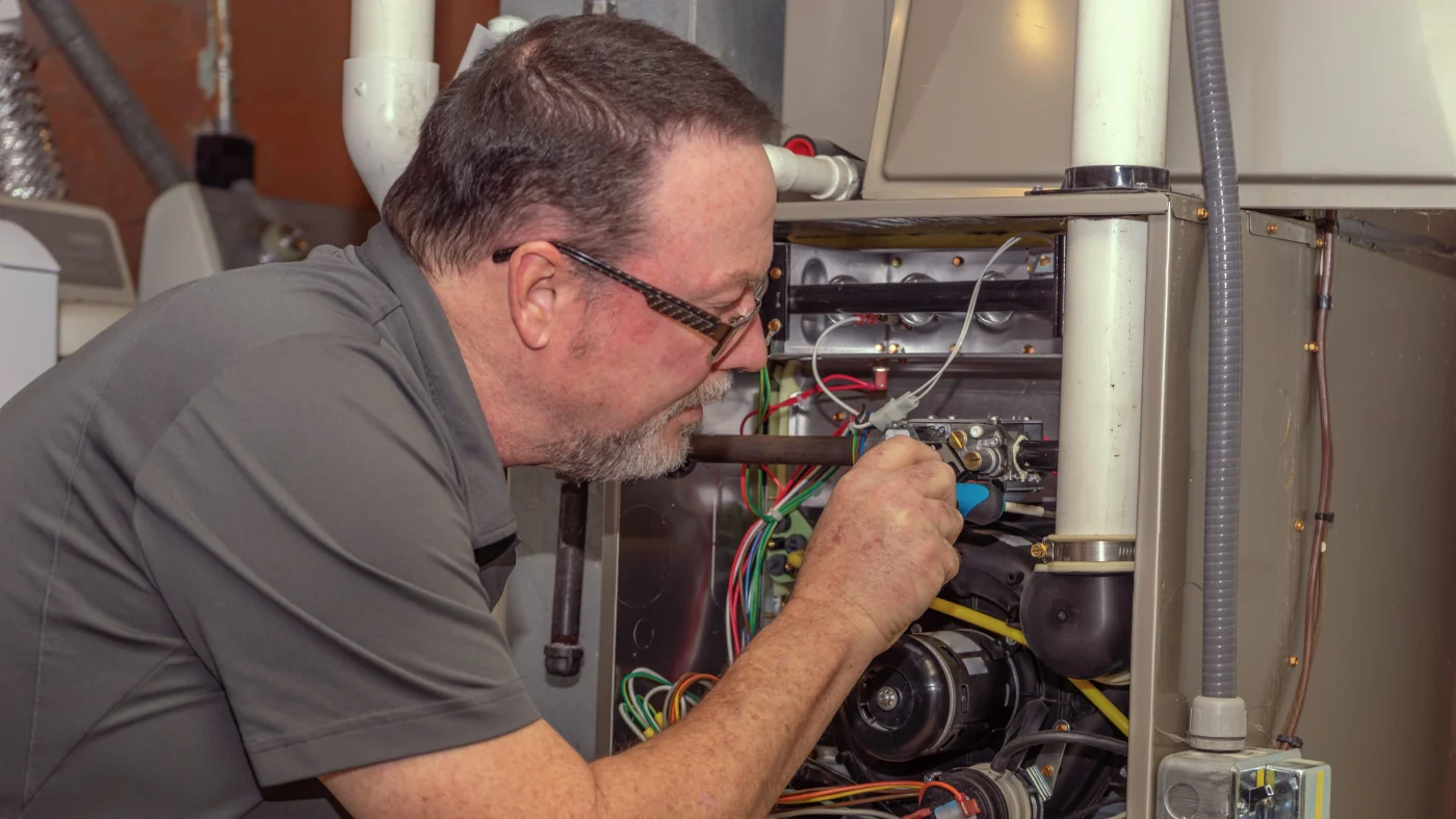 Heating Service – Ogden, Utah – Absolute Comfort Technician with Absolute Comfort Heating & Air Conditioning servicing the furnace of an Ogden area home.
