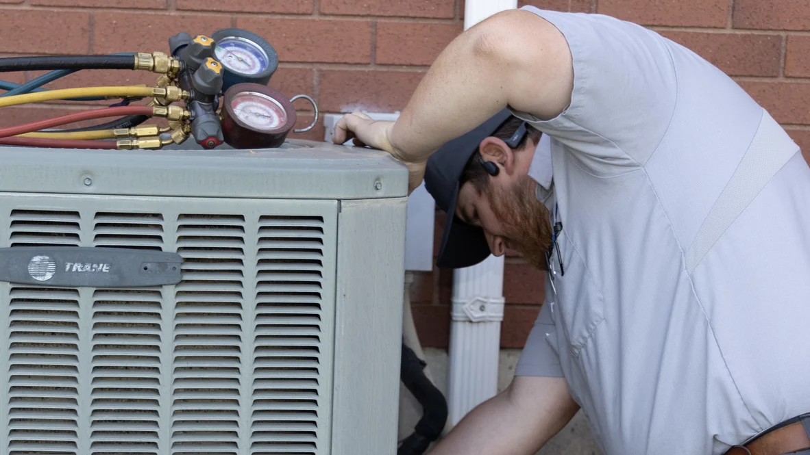 Heat Pump Maintenance Tune Up Comfort Club Ogden Heating Cooling Absolute Comfort technician cleans AC condenser during maintenance